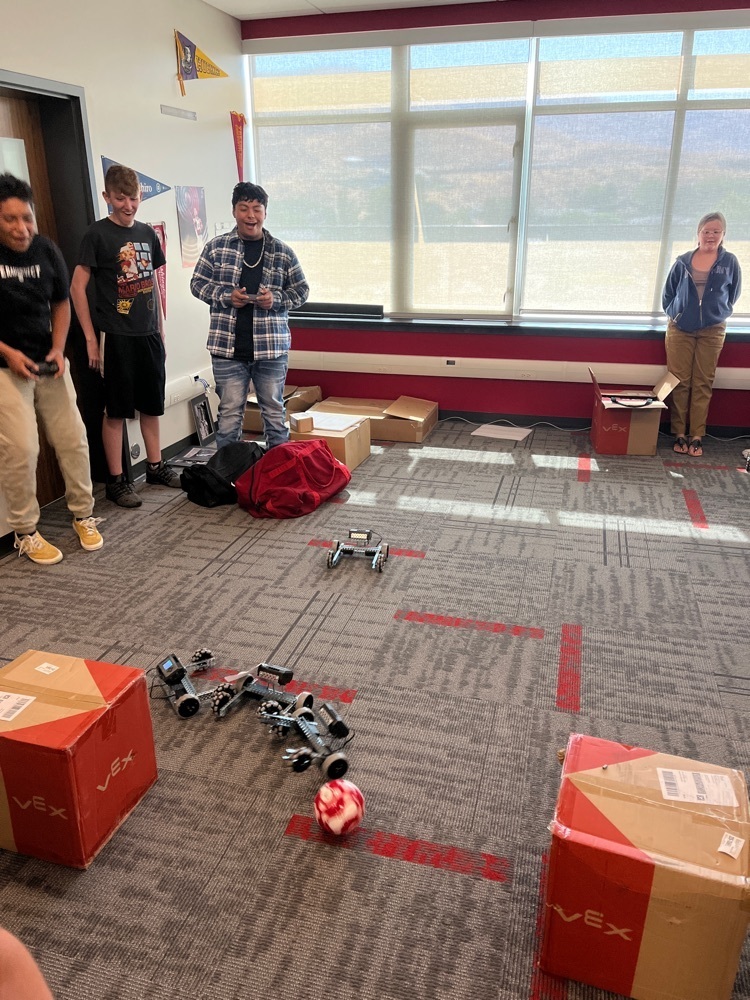students playing soccer with robots