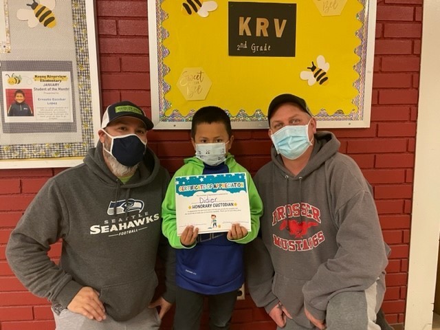 Child holding a certificate between two custodians